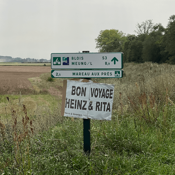 Panneau en carton Bon Voyage Heinz & Rita sous une signalisation vélo